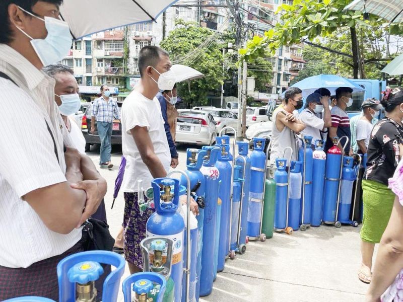 People queue up with their oxygen tanks outside an oxygen refill station in Pazundaung township in Yangon on July 11. (AP Photo)